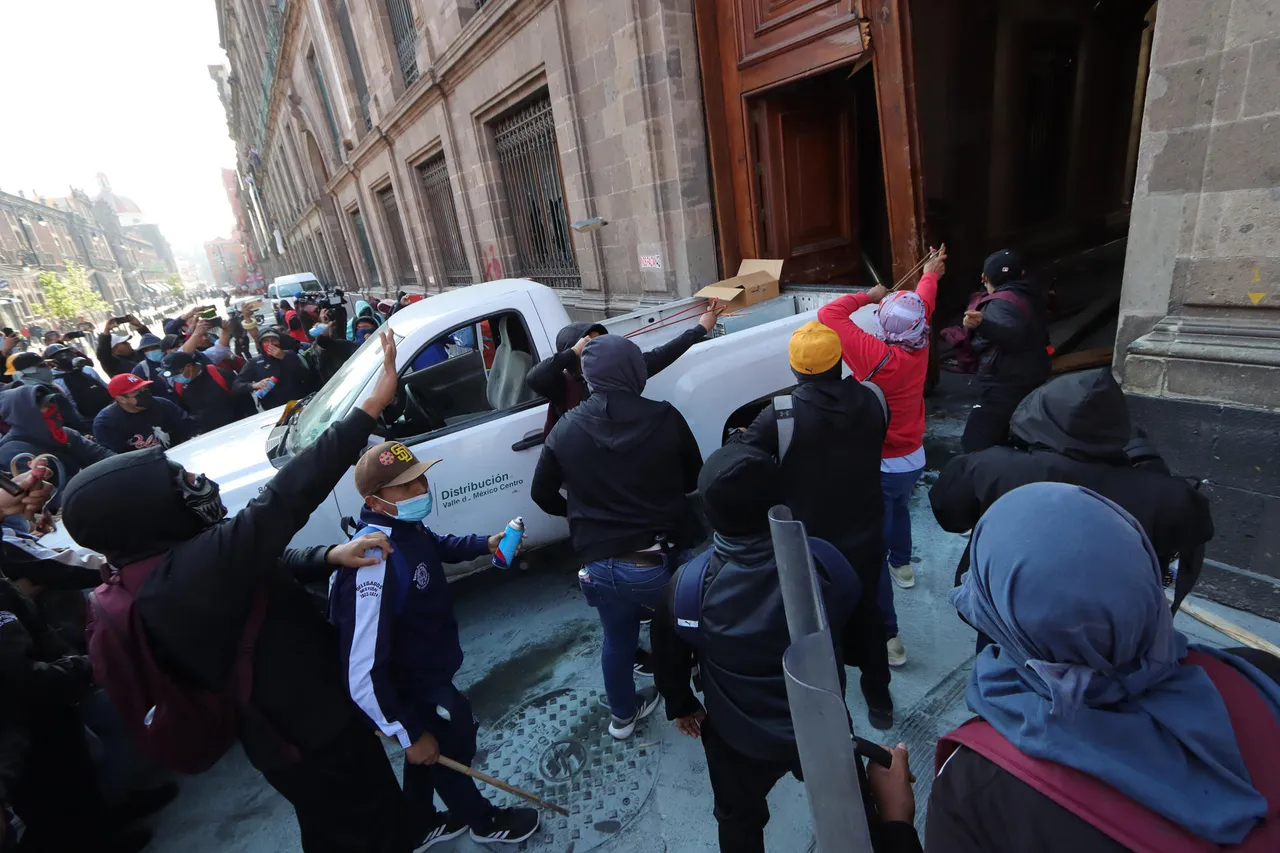 Jóvenes de Ayotzinapa derriban una puerta del Palacio Nacional con López Obrador adentro