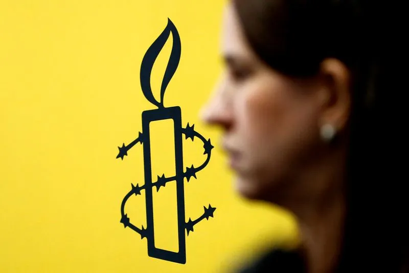 Imagen de archivo referencial del logo de Amnistía Internacional junto a la directora de Mujeres En Linea, Luisa Kislinger, durante una conferencia de prensa en Caracas