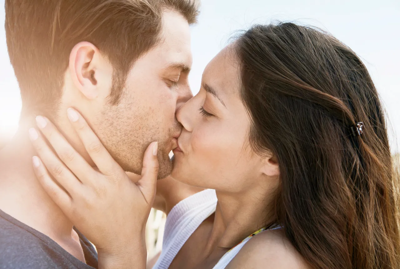 Spain, Majorca, Young couple kissing on boardwalk, close up