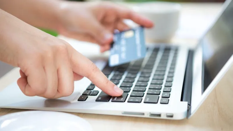 Hands holding a credit card and using laptop computer for online shopping