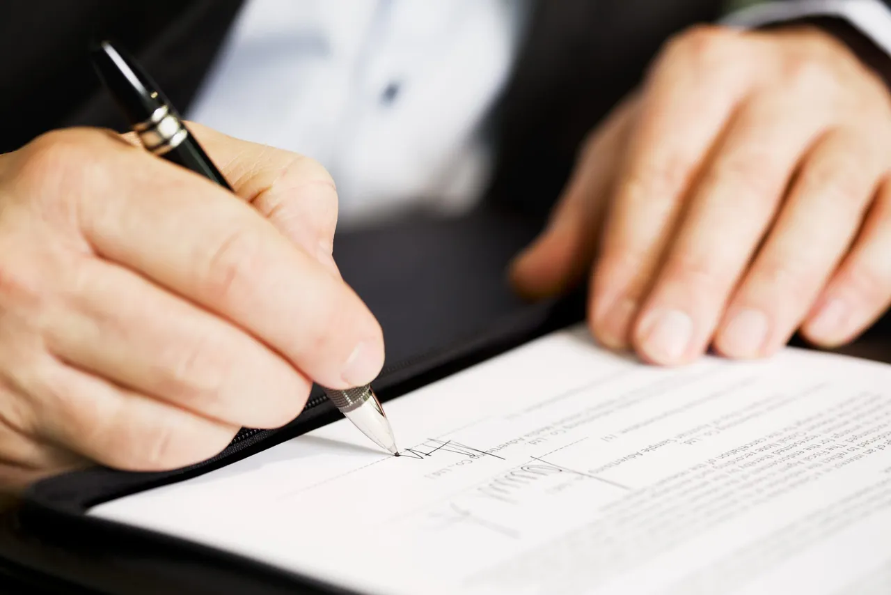 Close up of businessman signing a contract.