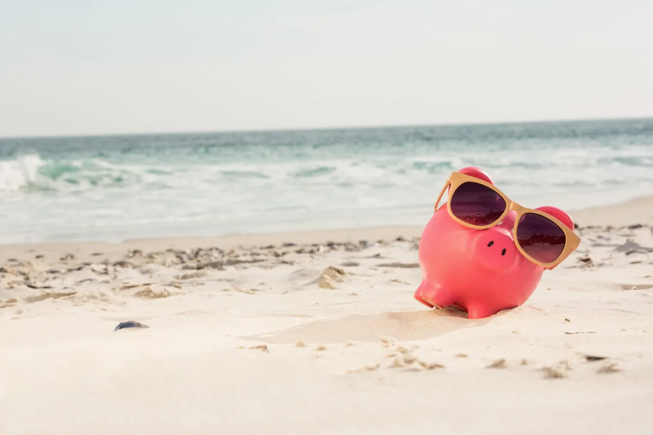 Piggy bank with sunglasses kept on sand