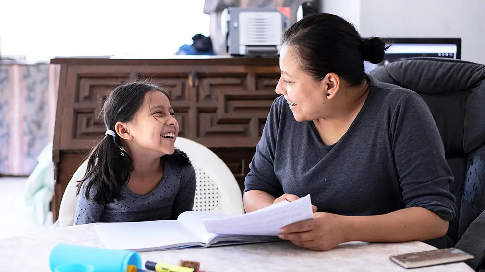 Mujer y niña sentadas sonriendo 